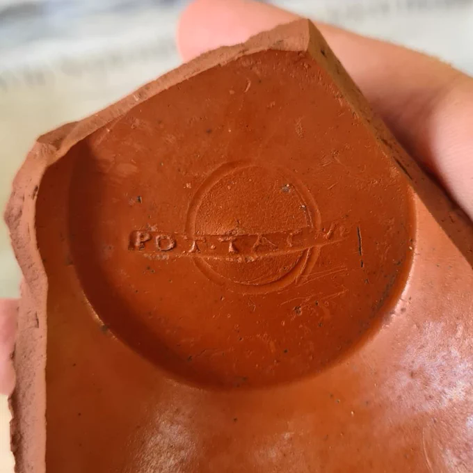 Shiny orange Samian ware pot with the letters POTTACV stamped into the base