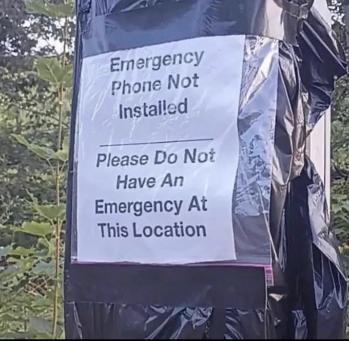 Plastic wrapped phone box with sign reading “Emergency phone not installed, please do not have an emergency at this location”
