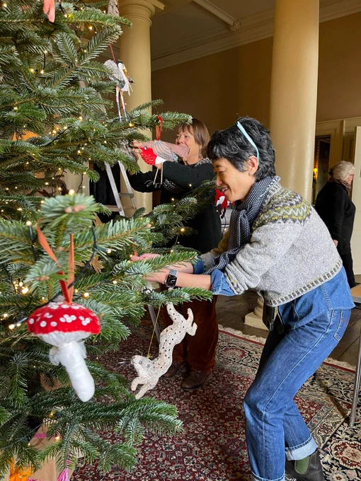 Two ladies adding woodland themed decorations to a Christmas tree at Dinefwr.