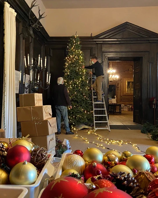 Staff adding lights and decorations to a Christmas tree at Tredegar House.