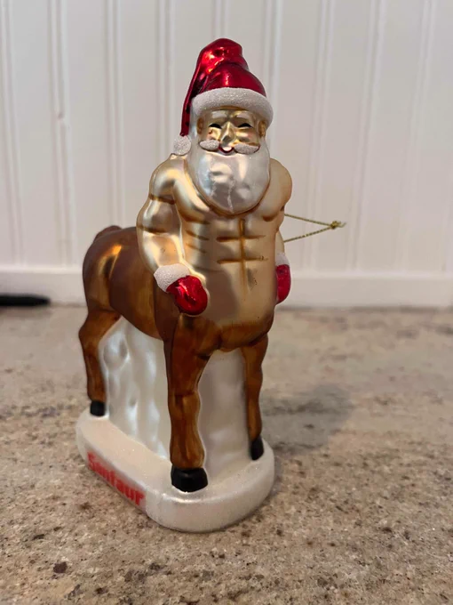 A Christmas tree ornament depicting a weirdly buff Santa Claus Centaur with a terrifying face.