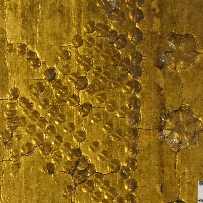 Micorscopic image of the gilded, punched background, showing the round punch marks consisting of two semicircles. 