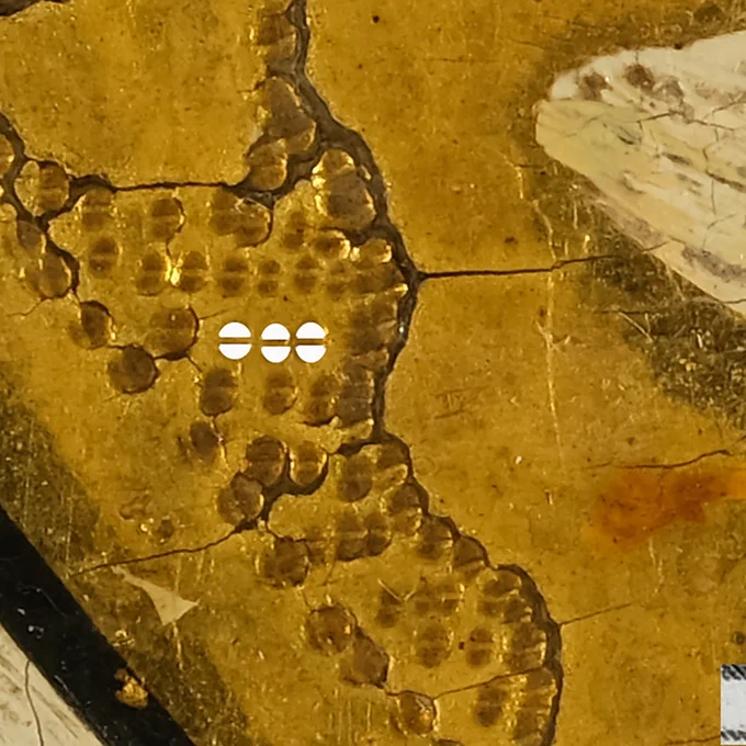Micorscopic image of the gilded, punched background, showing the round punch marks consisting of two semicircles. 