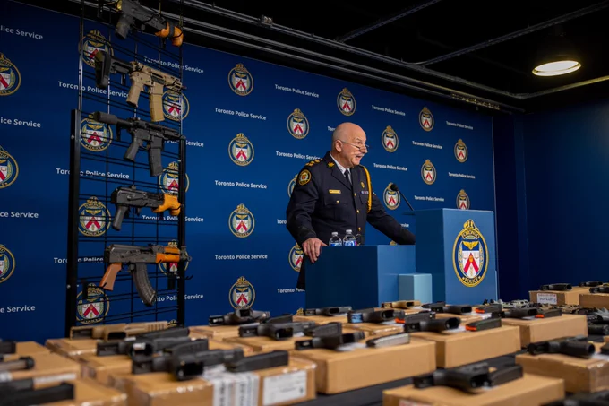 Police officer at podium with display of guns