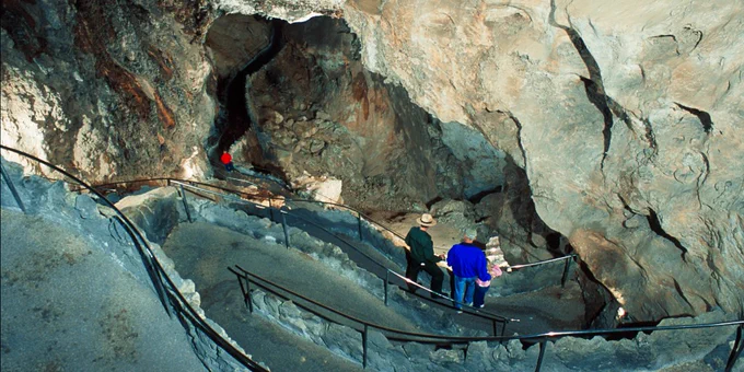 Three visitors and a National Park Service ranger stand on the entrance trail into Carlsbad Cavern, New Mexico.