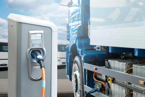 Photo from the article: Picture of a truck at an electric charging station. Caption: “The new climate law will unleash critical investments that make fleet electrification easier.”