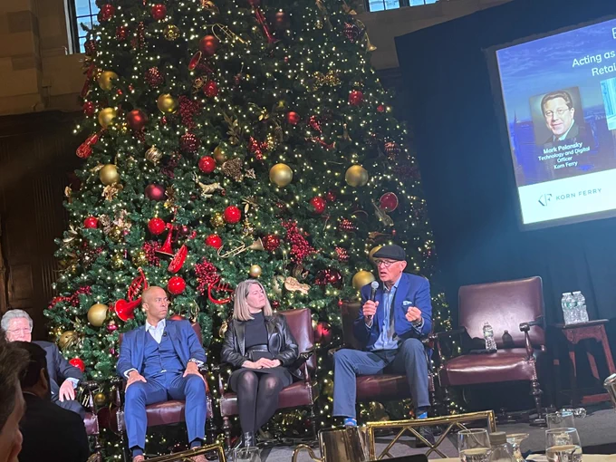 From left, Chuck Gray, Mark Polansky, Renee Arrington and Tony Leng sit in a row of chairs in front of a large Christmas tree during a panel discussion.
