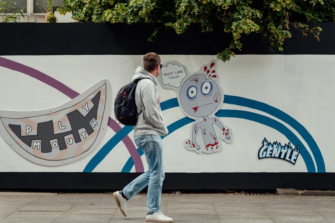 A mural with cartoon designs, a person walks past it