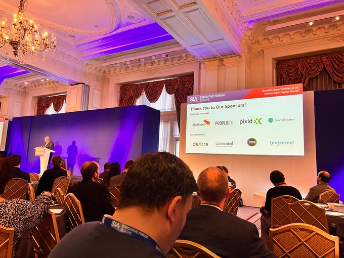 John Nurthen giving opening Keynote speech at SIA Executive Forum in London. Displayed slide shows the sponsors including Pixid
