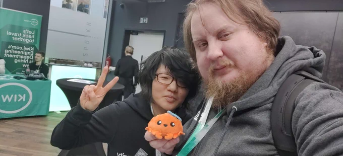 Two people in a selfie, posing with an orange crab plushie.