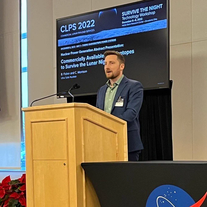 Ben Fisher, EmberCore Product Manager at @USNCTech, stands at a podium to present the Ultra Safe Nuclear team's work on using commercially available radioisotopes to enable technology on the lunar surface to survive the extreme cold of lunar night.