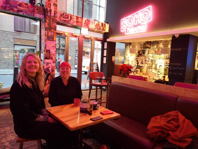 Two young women sit at a table in Soho Theatre's bar. 