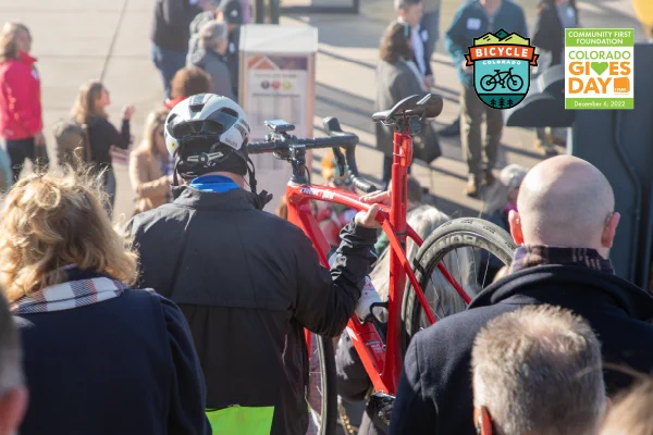 A person carrying their bike down stairs facing away from the camera in a crowd of people.