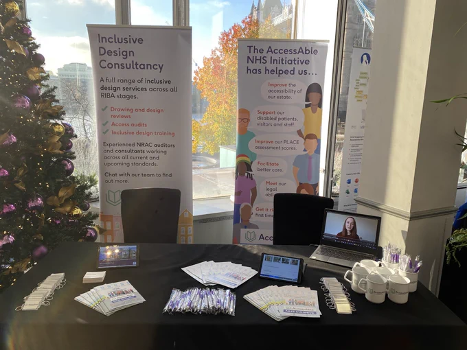 View of AccessAble’s stand at the Disability Summit. There are pens, key rings, tablets displaying the AccessAble website, mugs and banner stands highlighting AccessAble’s services.
