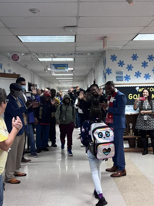 Two students walk down the hall while the JCPS Flash Dads clap and cheer.