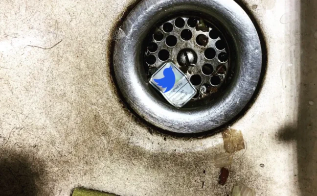 Symbolbild, silberner Twitter Sticker im dreckigen Küchenabfluss