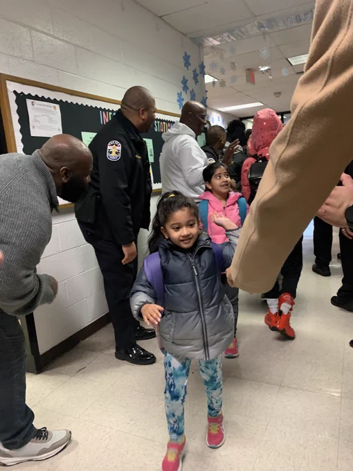 Two students walk through the hall lined with JCPS Flash Dads at Goldsmith Elementary School.