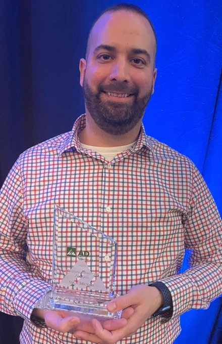 Evan holding the clear trophy for the Digital Mindset Award