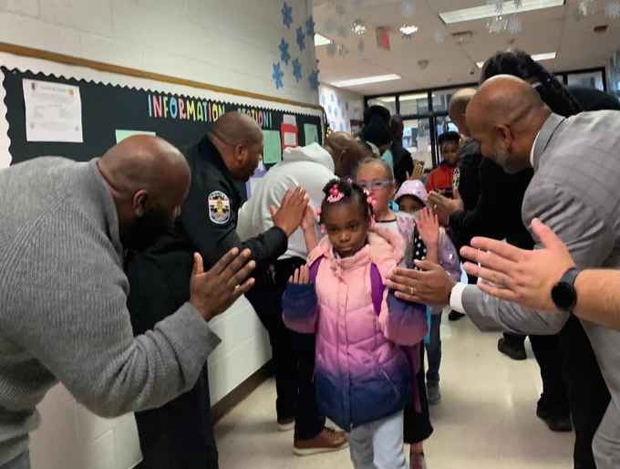 Students walk down the hall and slap hands with the JCPS Flash Dads.