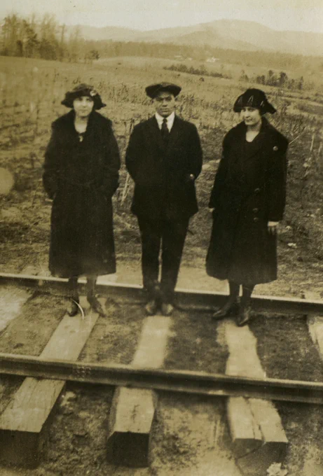 This image shows three students from the Appalachian Training School (1903-1925) standing on the Linville River railroad tracks in the summer of 1923. The railroad, nicknamed the Tweetsie Railroad, ran from Johnson City, TN, to Boone, NC, from 1918 to 1940.