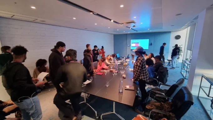 Creativity Works trainees gathered around a boardroom table in the Merkle offices.