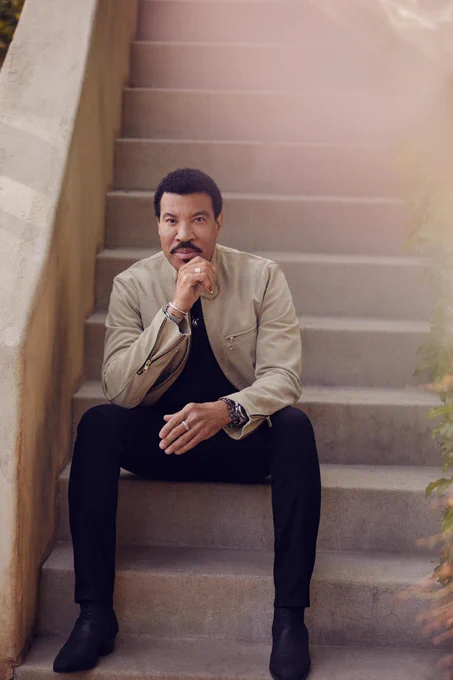 A photo of a man, musician Lionel Richie, sitting on a staircase.