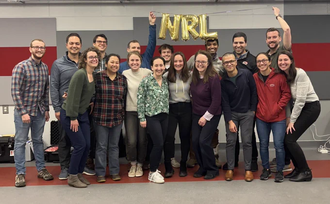 Group photo of the Neuromotor Recovery Lab. Two members are holding up balloons that say “NRL”