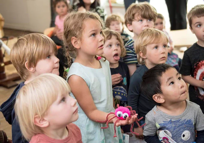 A group of young children look captivated by a storyteller