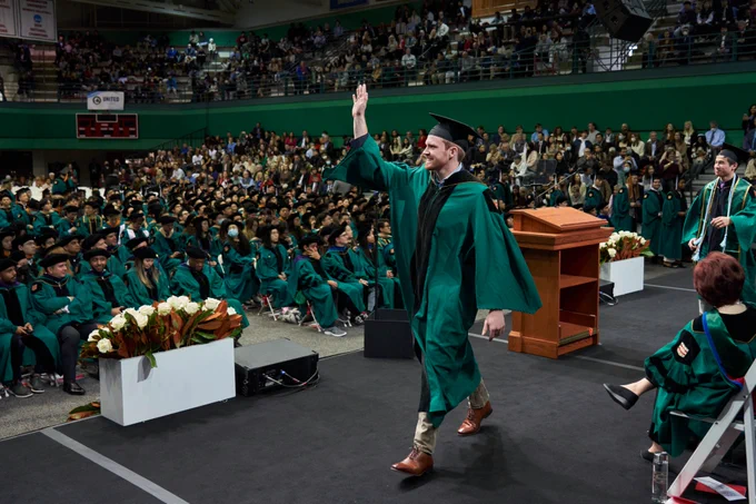 #WashU22 graduate smiling and waving while walking across the stage during WashU's December Recognition Ceremony.