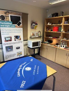 Photo taken in our Resources room of our home daily living sections showing a talking microwave, magnifiers, large print calendars and games, kitchen untesils and more.