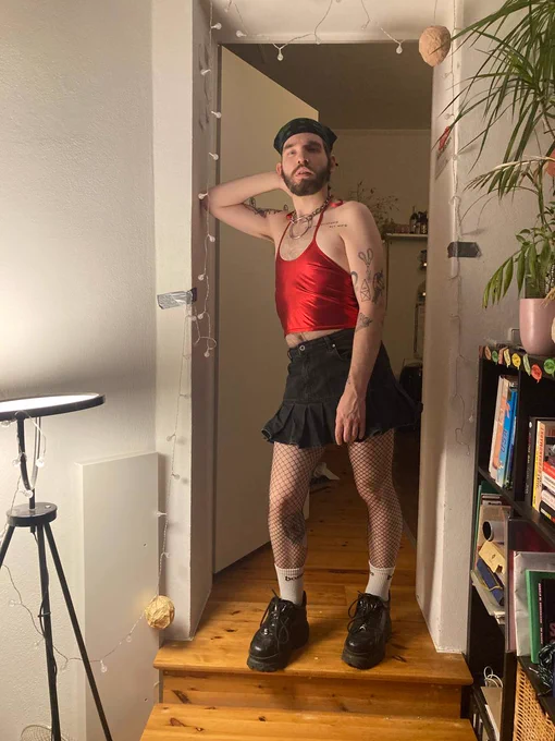 Timi postet für die Kamera.
Sier hat ein rotes Top und einen Rock an.