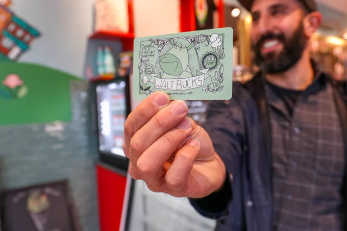 Jordan holds an Ample Hills Walt bucks gift card and smiles.