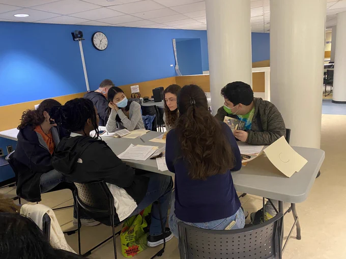 A group of high school students sitting around a folding table and participating in a discussion.