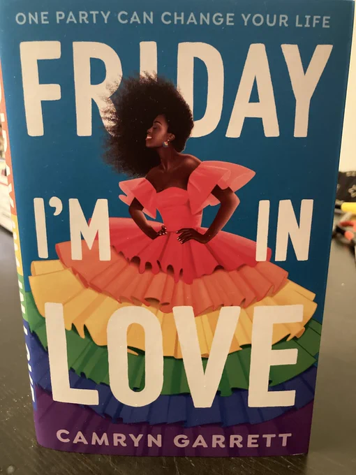The cover of the book! There's a black girl in a gigantic pouffy rainbow dress with the words FRIDAY I'M IN LOVE in white block letters. At the very top, it reads "one party can change your life."