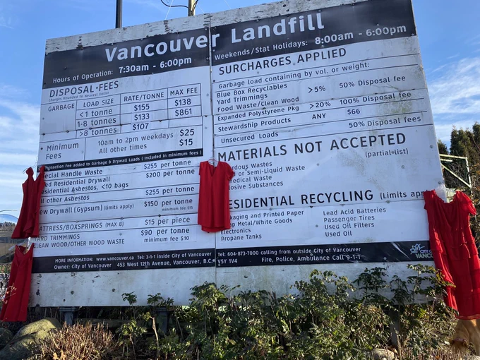 Red dresses hanging on the Vancouver lamdfill sign. 