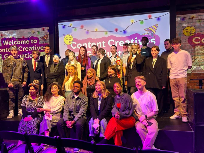 The autumn cohort of Content Creatives 2022 smile on stage at their graduation