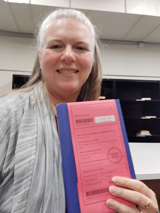  A person holds a book that has a pink ReShare slip attached to the cover.