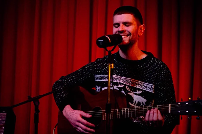 PKYB playing guitar in a festive jumper