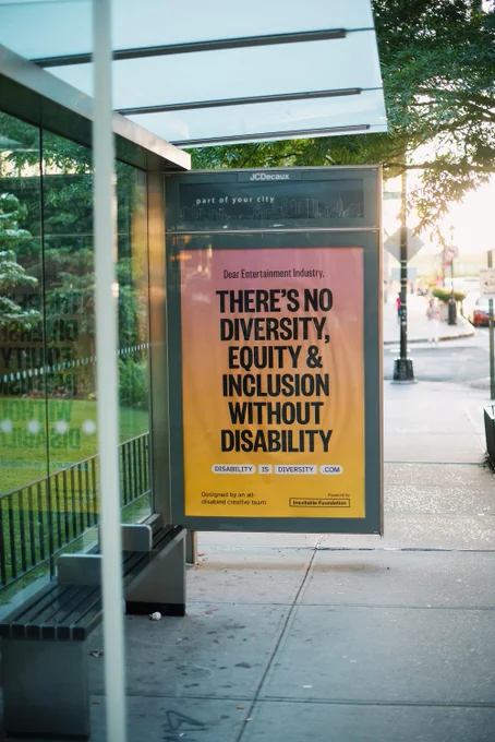 A pink and yellow gradient billboard on a bus stop with bold black text that reads: "There's no diversity, equity & inclusion without disability." 