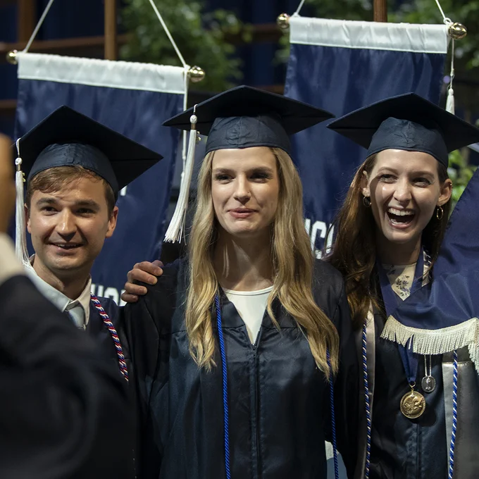 Three Liberal Arts graduates taking photos together after the spring 2022 commencement ceremony at the Bryce Jordan Center.