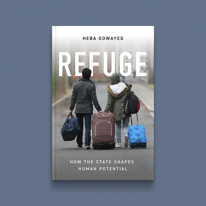 Slate grey background with book cover of Refuge. On cover is a pair of people walking down a paved road several bags of luggage. Title is in tall white letters at the top. 