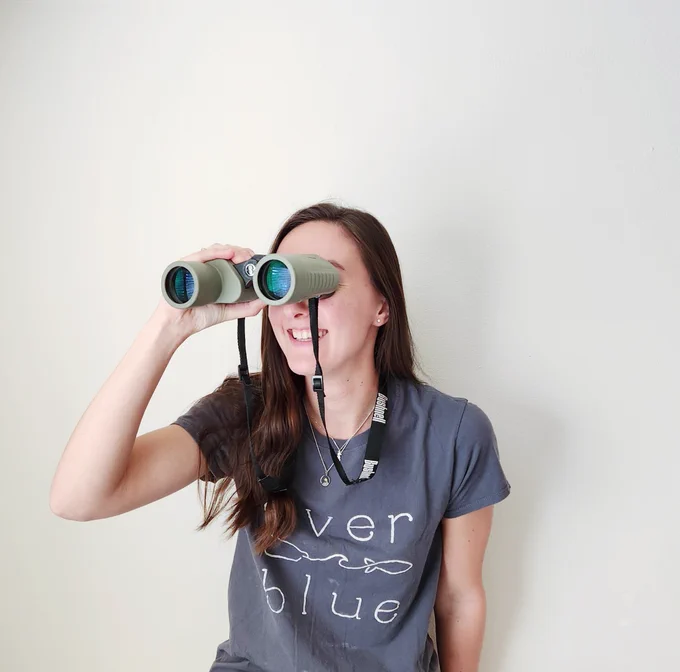 Team member Rachel looks through a pair of binoculars 