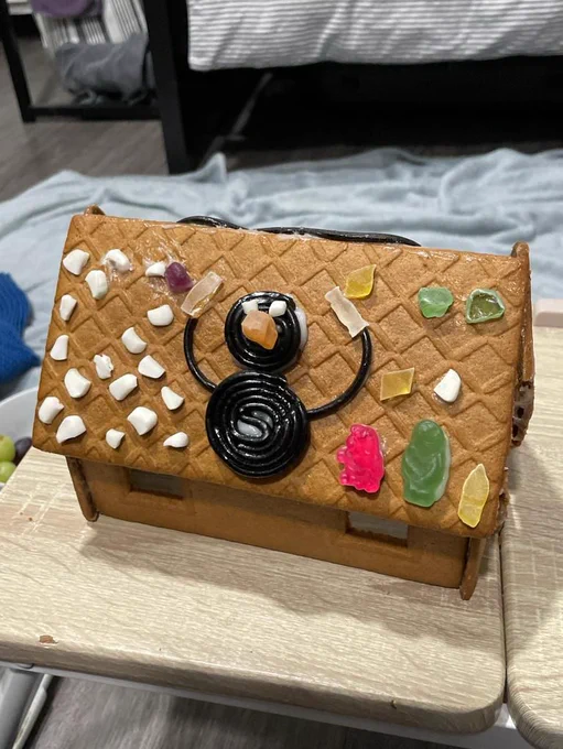 Portrait of a gingerbread house featuring Pingu the penguin made out of liquorice and accompanied by sweets