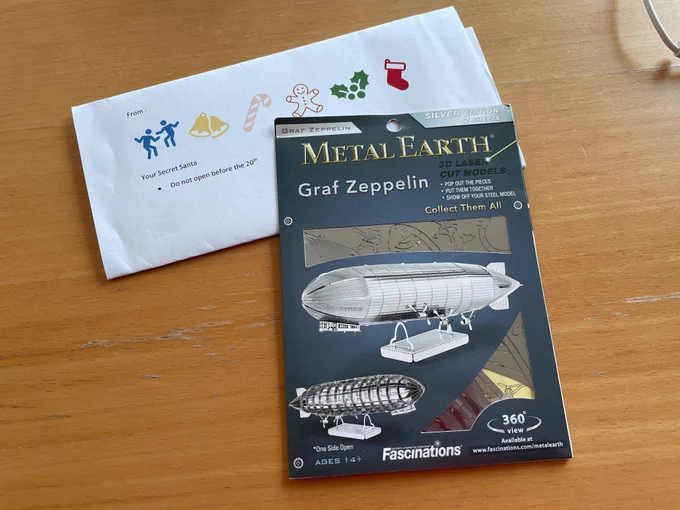 Secret Santa note (christmas pictograms)  and a Graf Zeppelin kit, currently unassembled, laser cut silver metal airship on a stand, solid on one side cutaway on the other. 