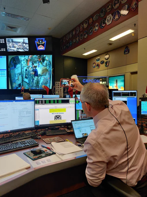 Canadian Astronaut David Saint-Jacques sits in Mission Control at NASA's Johnson Space Center while watching, on a large screen, NASA Astronauts Josh Cassada and Nicole Mann work on a spacesuit on the International Space Station.