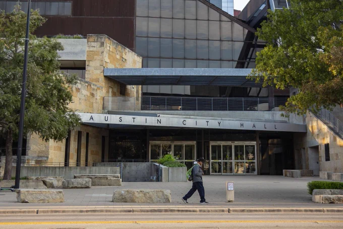 Person walks on the sidewalk in front of Austin City Hall. Photo by Julius Shieh.