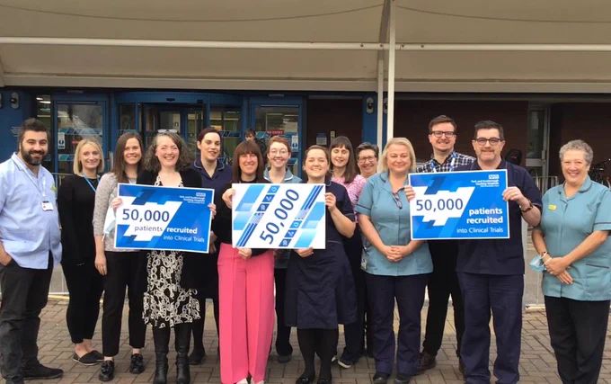 Staff from York Research stand outside York Hospital holding '50,000' signs to mark their achievement.