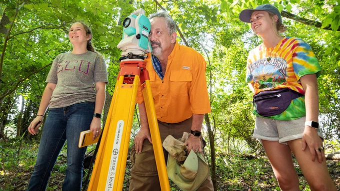 Anthropology professor Charles Ewen, center, works with students Mackenzie Mulkey and Regina Wheeler to locate and document gravesites at an abandoned cemetery in Ayden in 2021.