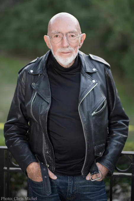 An image of Kip Thorne looking directly into the camera. He is wearing a black shirt and black leather jacket