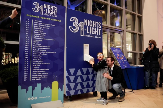 Mila presses on a large light switch at the 31 Nights of Light celebration.